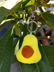 Avocado Plush Keychain. The avocado is almost the size of a real Avocado. It is cut in half to show the avocado and pit.